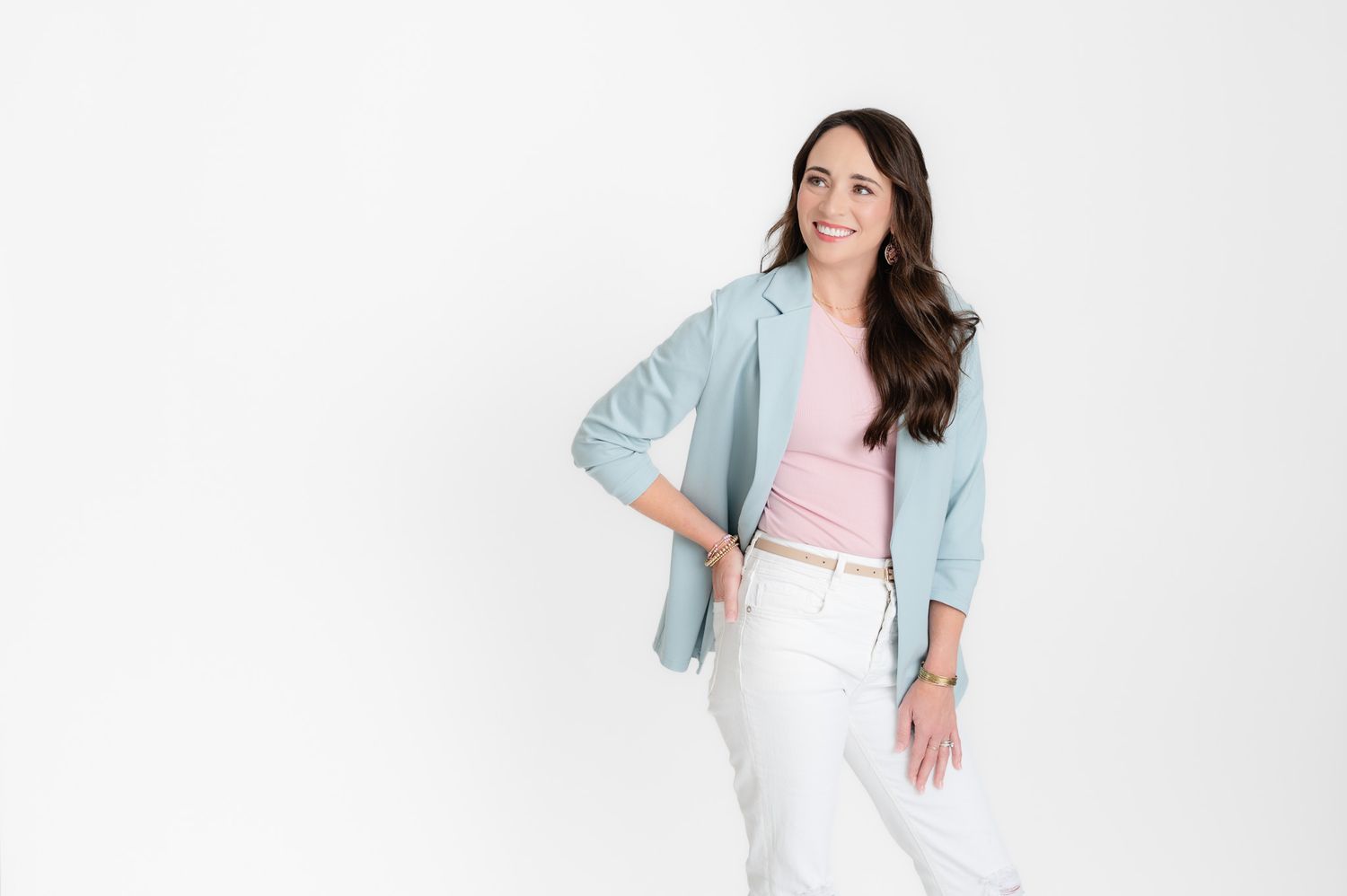 Professional headshot of a businesswoman wearing a beige blazer against dark background.