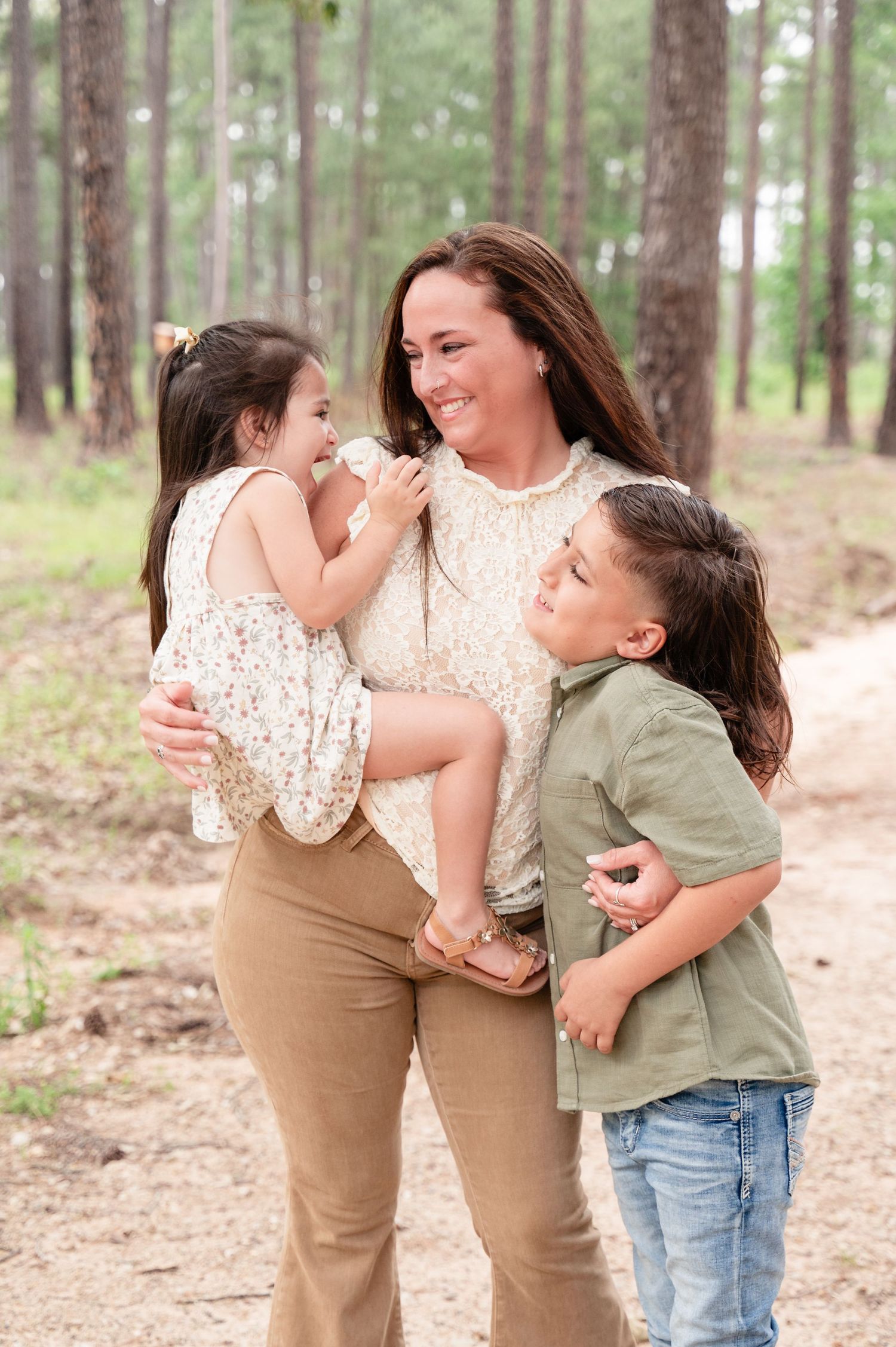 Joyful family moment captured on a nature trail surrounded by pine trees.