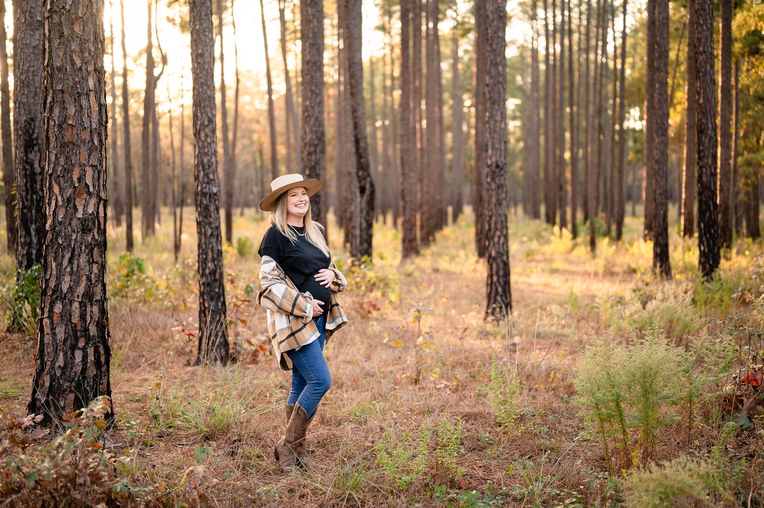 Portrait in wooded area during sunset among tall pine trees.