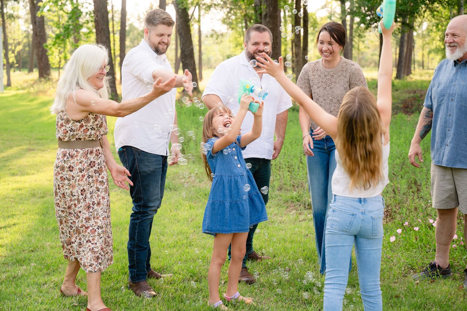 Group of people enjoying a fun outdoor gathering in a park with trees in the background.