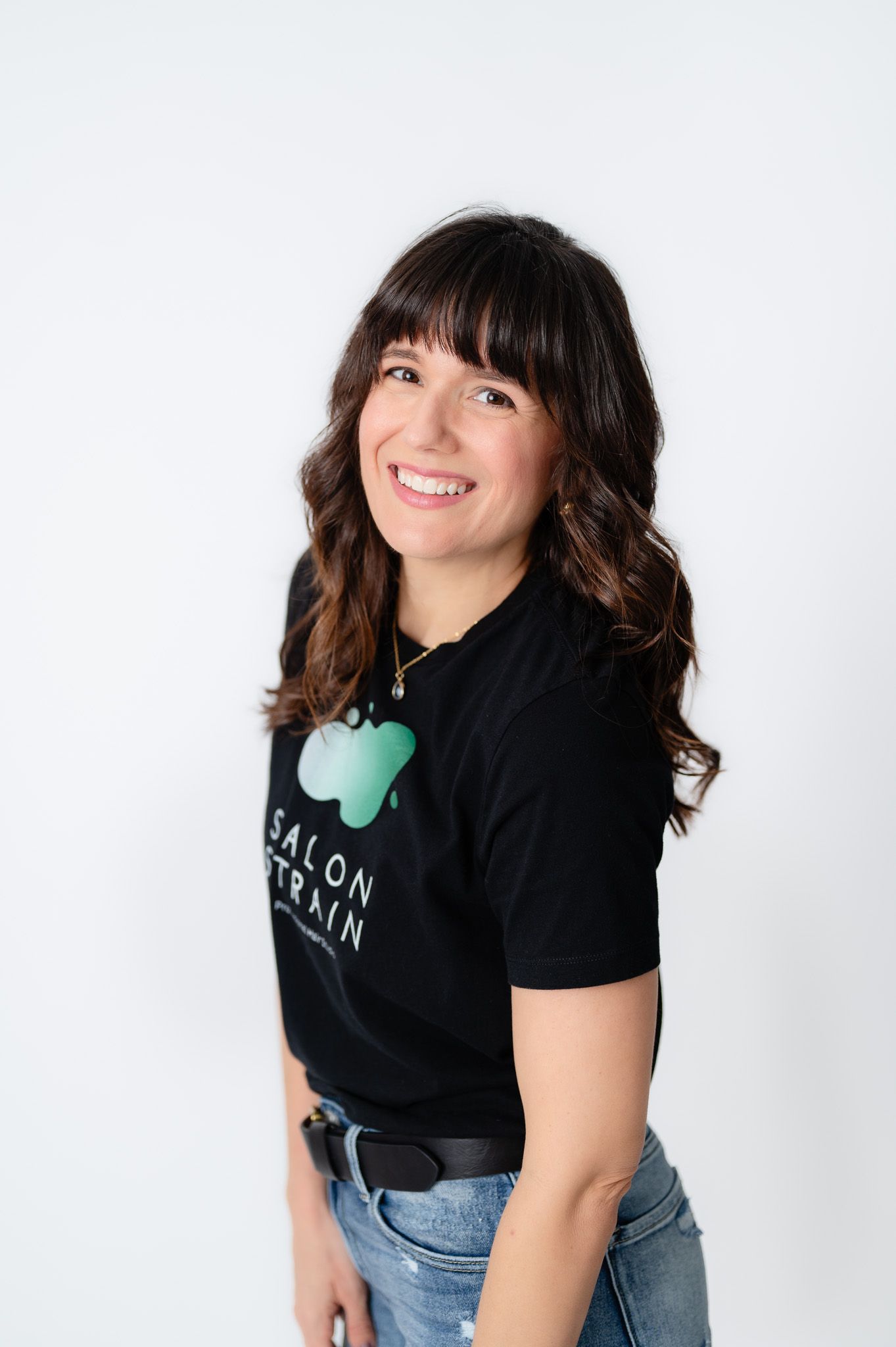 Woman in black t-shirt and jeans poses playfully against white background in three different poses.
