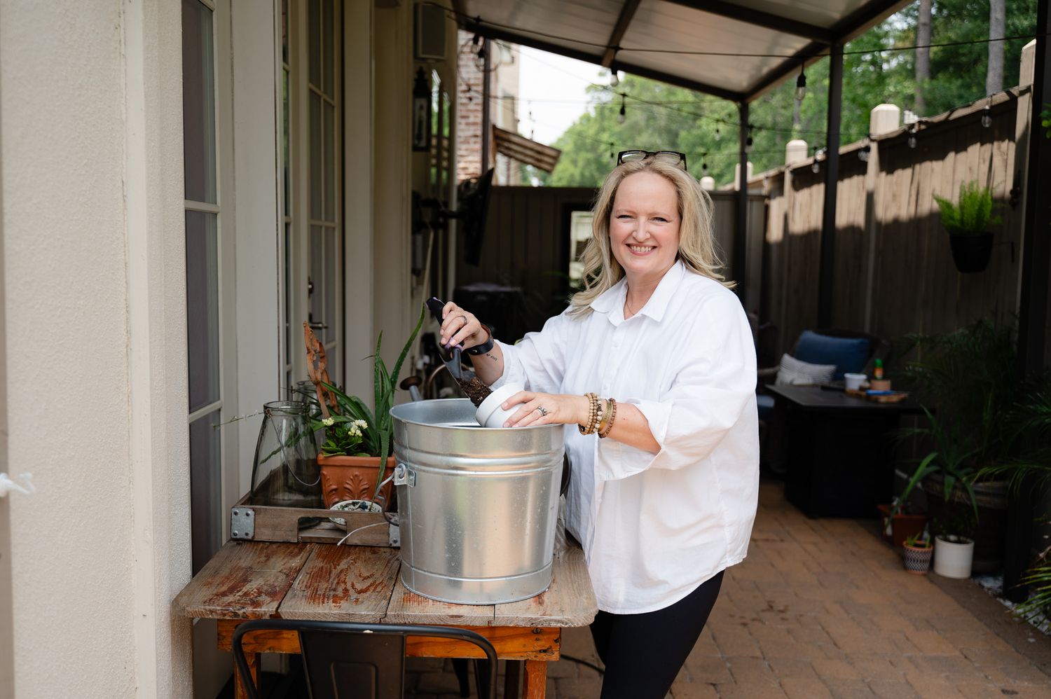 Person in white coat preparing food on outdoor patio with cooking equipment.