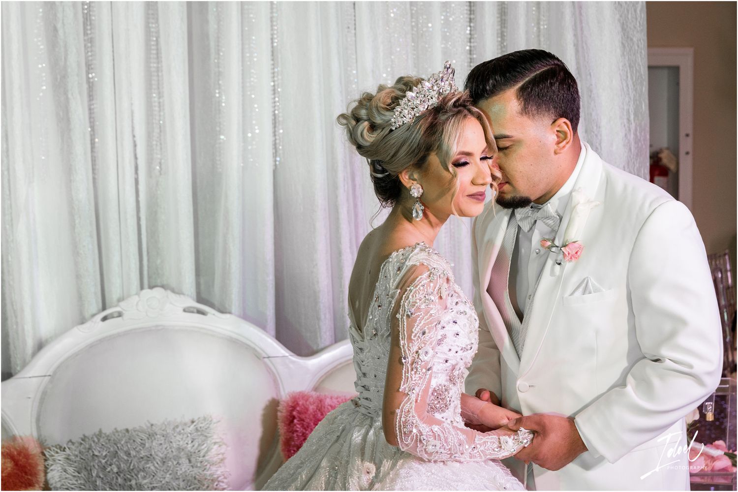 An intimate wedding portrait against a white backdrop with elegant attire.