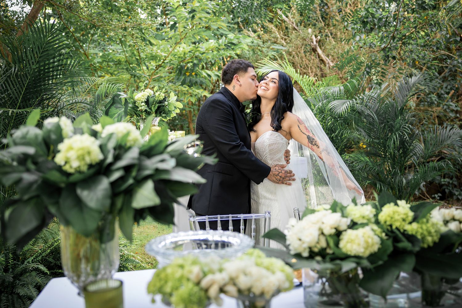 Garden wedding scene with lush greenery and white floral centerpieces.