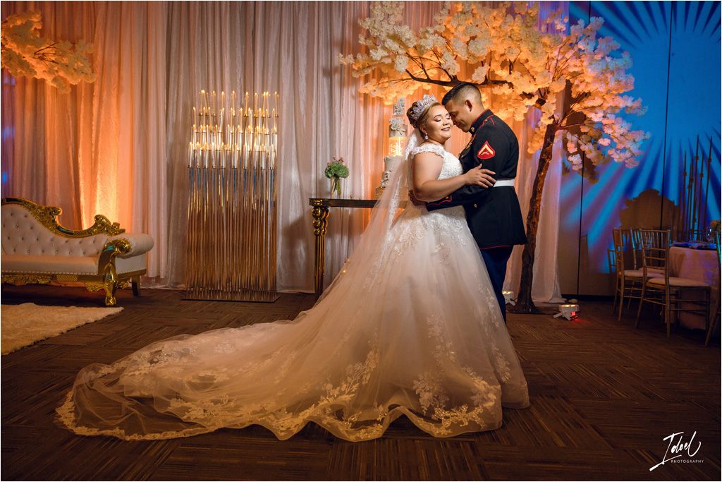 A wedding reception scene with a couple dancing under orange-lit cherry blossom decor.