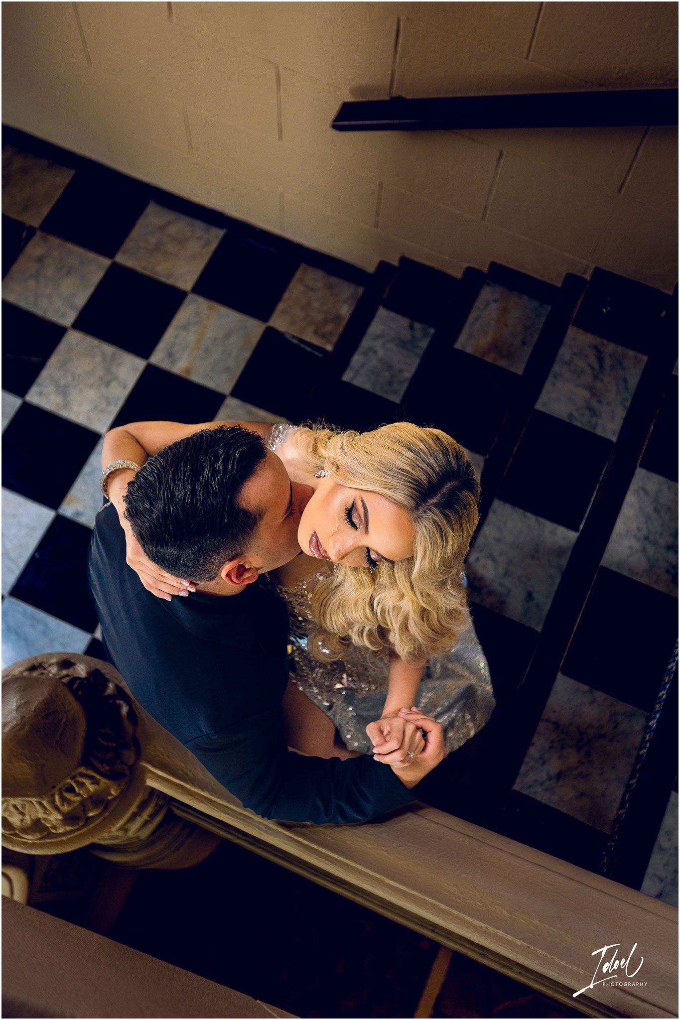 Overhead view of couple dancing on checkered floor in elegant formal attire.