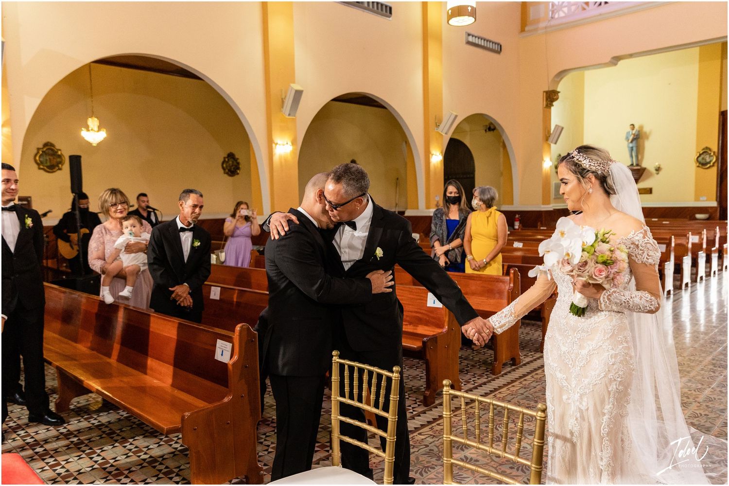 Emotional wedding celebration moment in a church aisle with guests and ornate architecture.