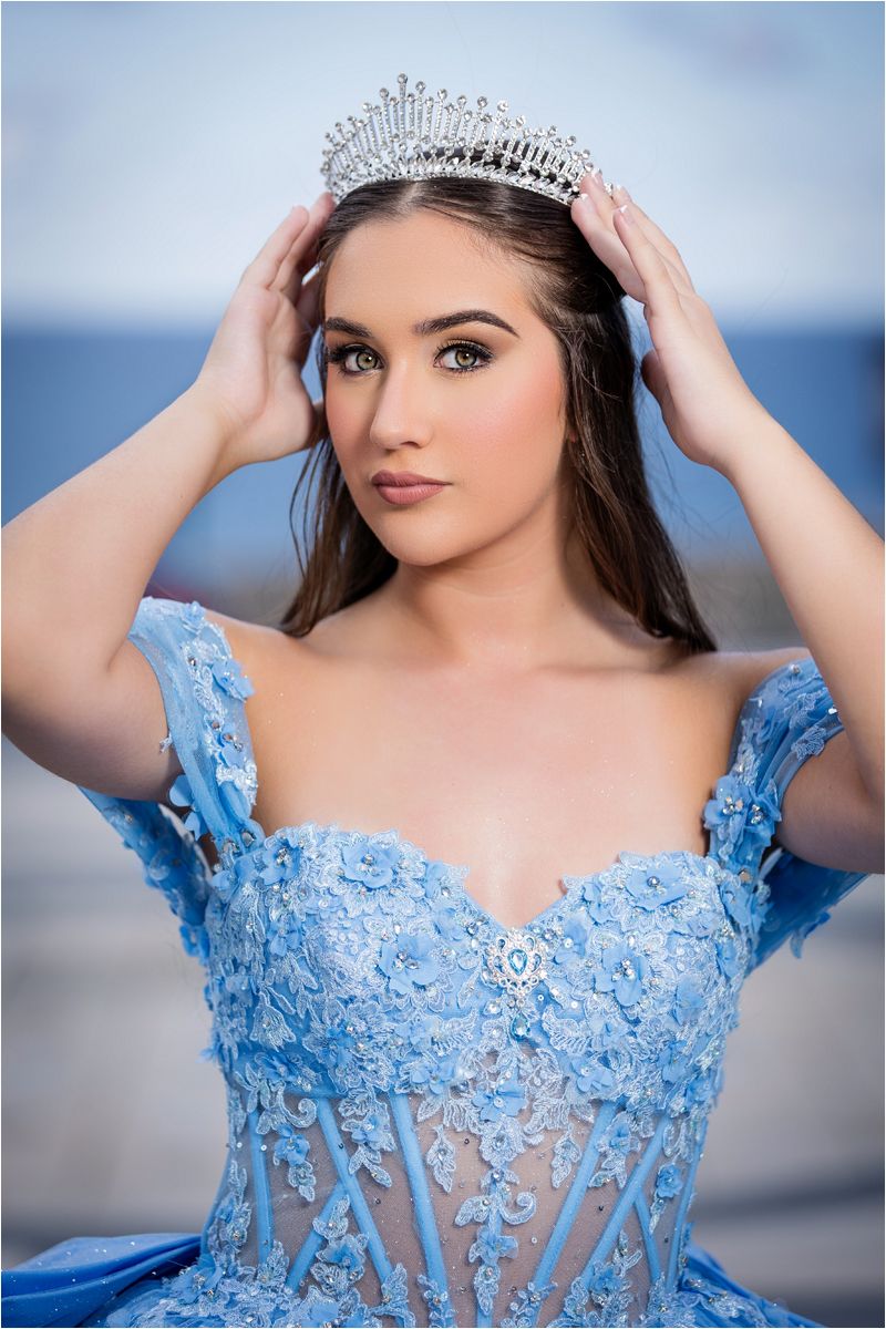Elegant portrait series in light blue lace gown and crystal crown against soft background.
