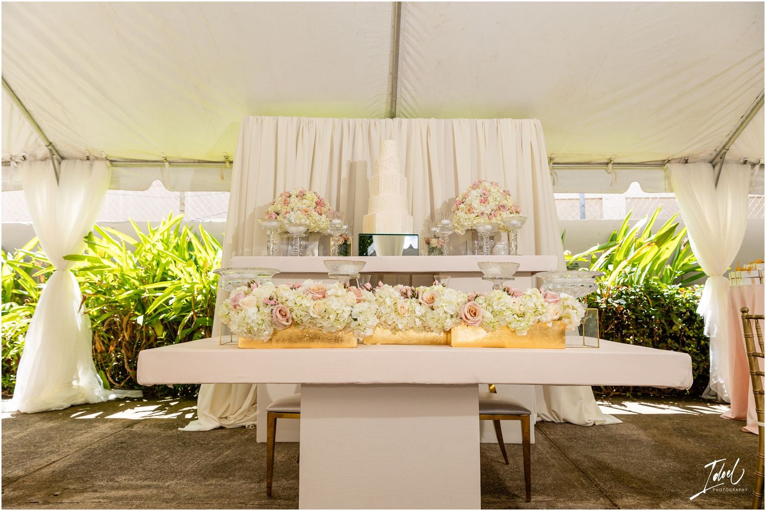 An elegant white wedding reception tent setup with draped fabric and floral decorations.