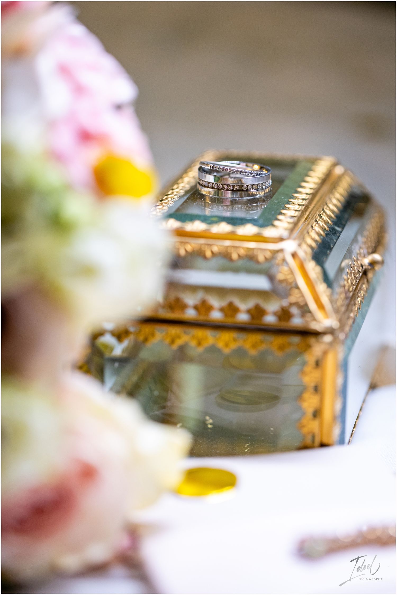 Wedding rings displayed on an ornate gold mirrored jewelry box with floral decorations.