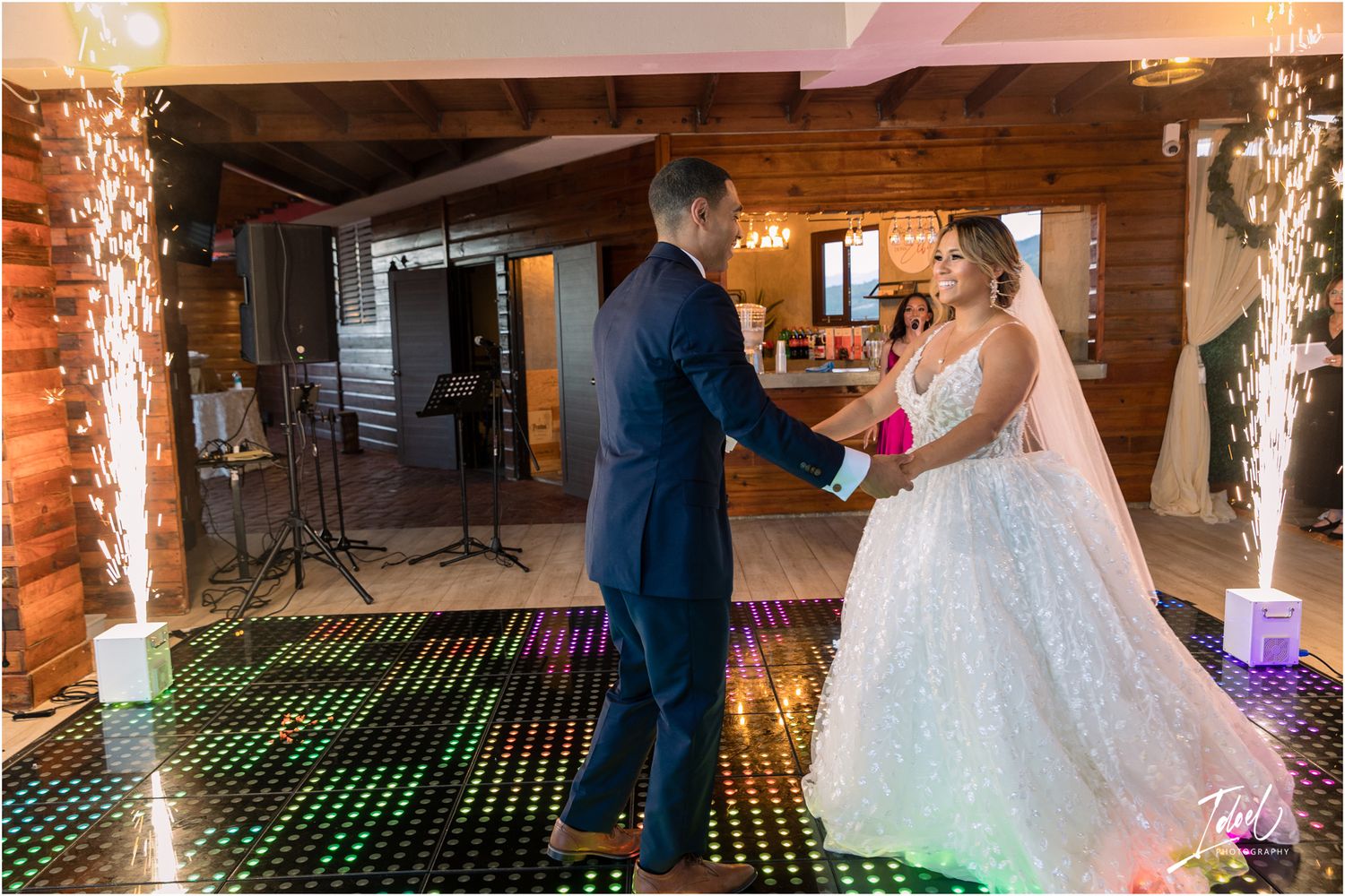 Couple dancing on a colorful LED lit dance floor in a rustic wooden venue.