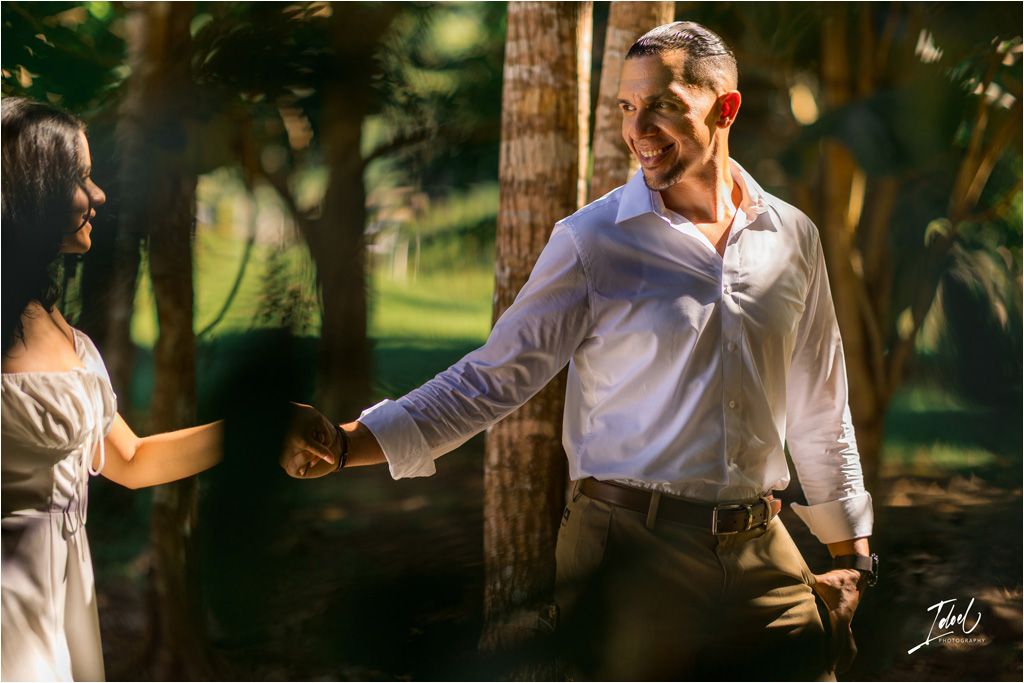 A romantic outdoor photoshoot in a garden setting with sunlight filtering through the trees, creating a warm atmosphere.
