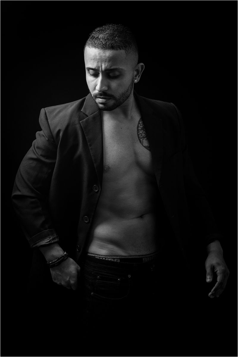 Artistic black and white photo series showing a shirtless person in dark blazer against black background.