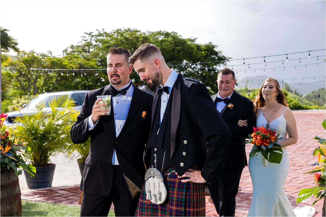 Wedding party in formal attire including traditional Scottish kilts celebrating outdoors.