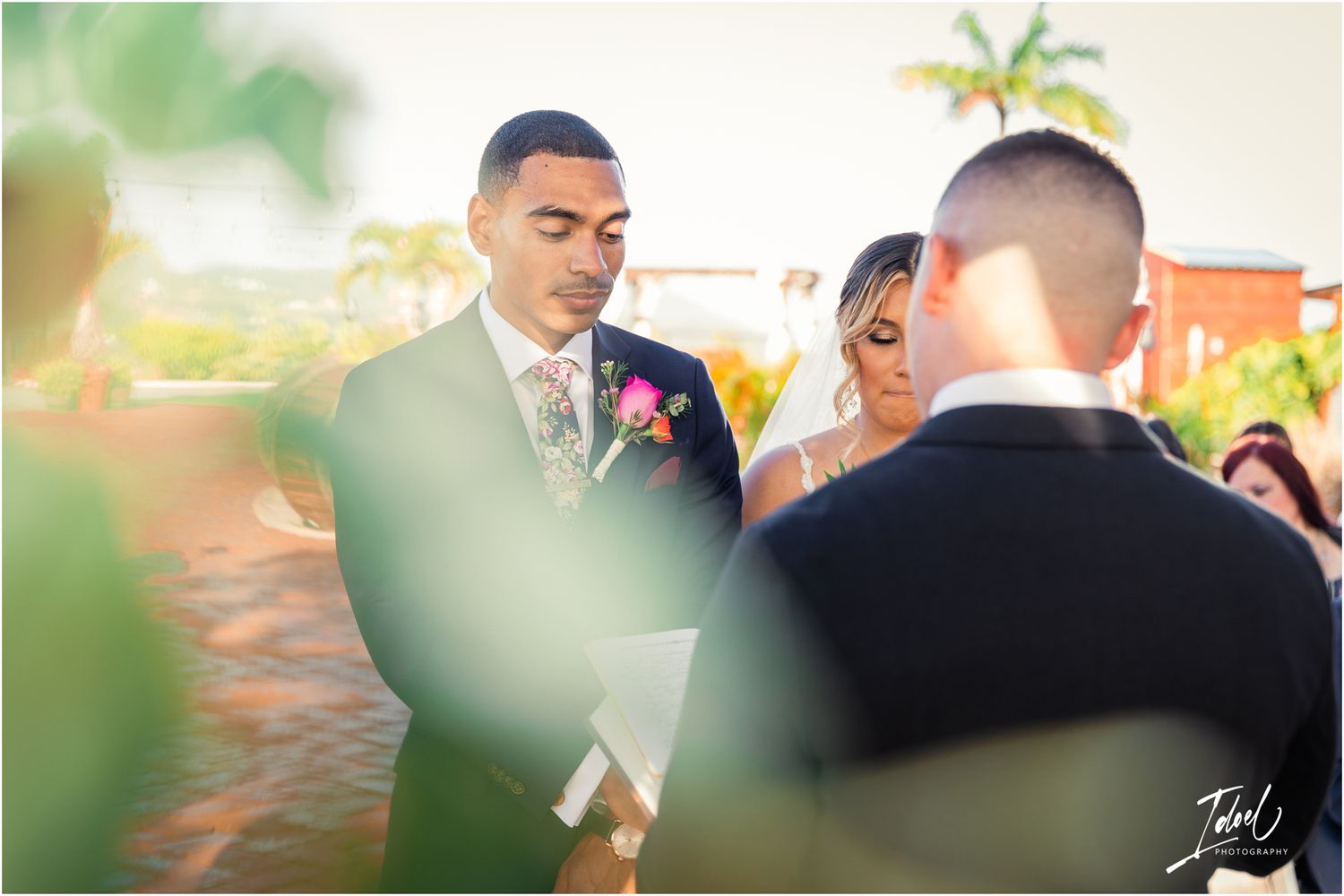 Wedding ceremony captured through greenery during an intimate outdoor celebration.