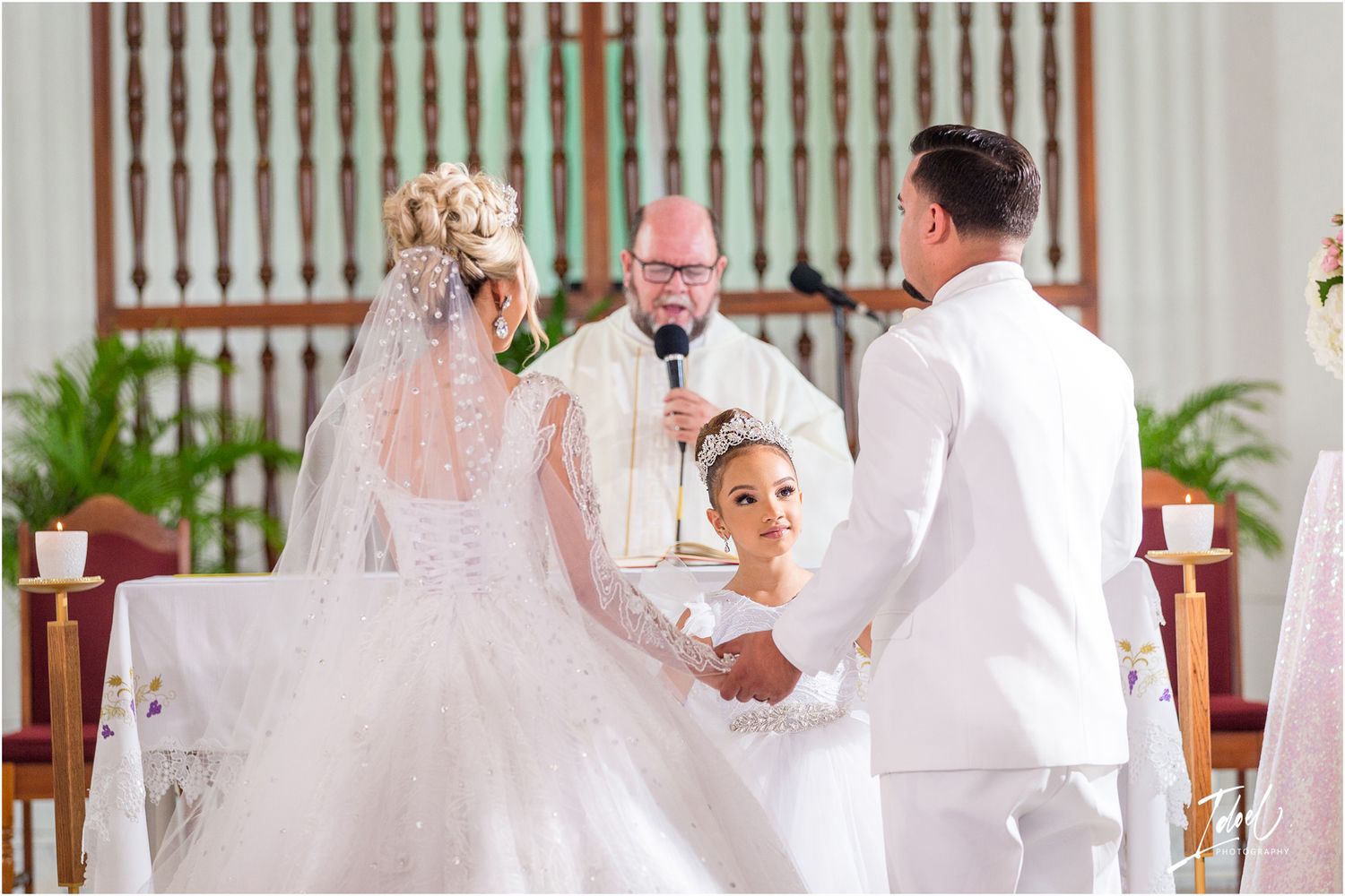 A traditional church wedding ceremony with pink floral arrangements and white decor.