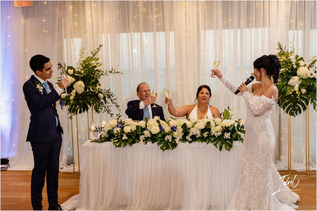 Wedding reception celebration with toasts and cheers at the head table.