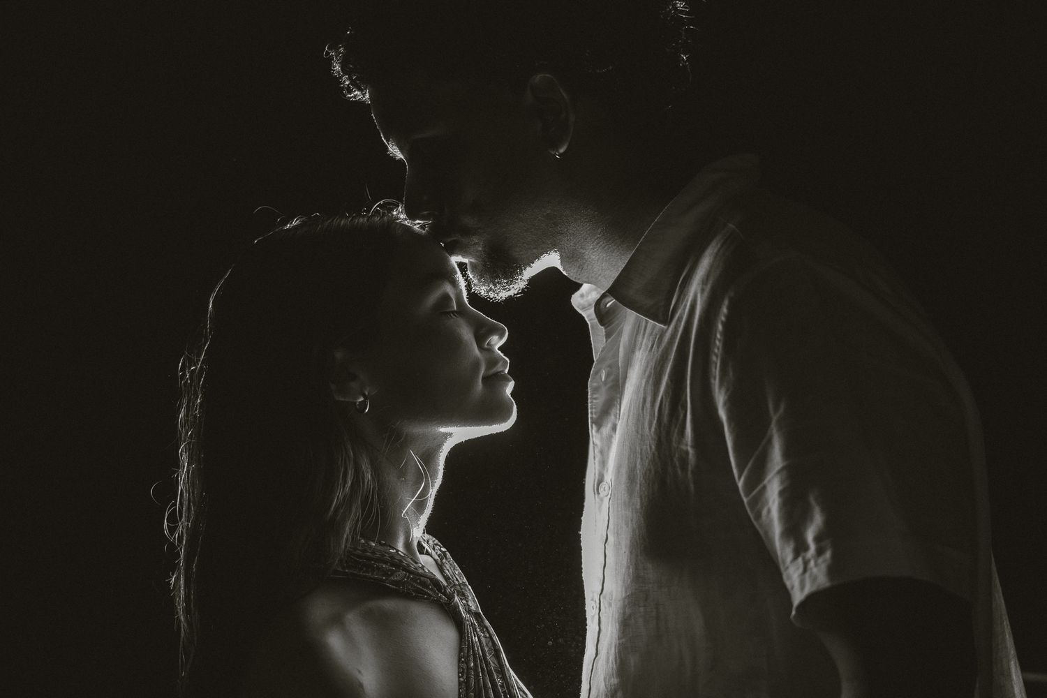 Dramatic black and white silhouettes of couple in intimate moment.