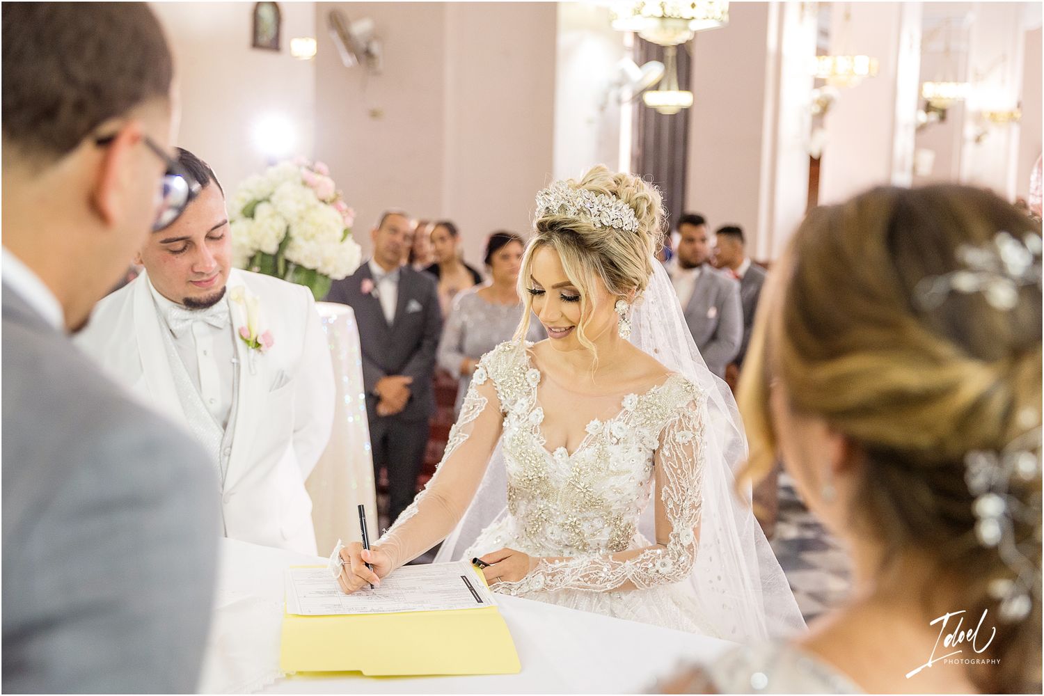 A signing ceremony during a traditional church wedding with guests watching in the background.