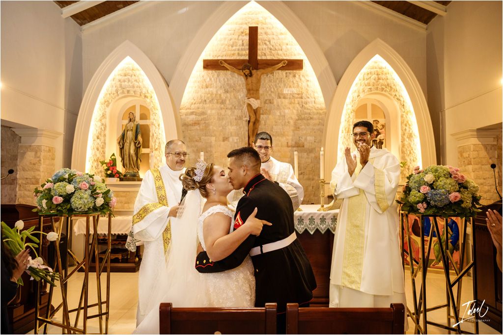 Wedding ceremony in progress at an altar with illuminated stone arches and floral arrangements.