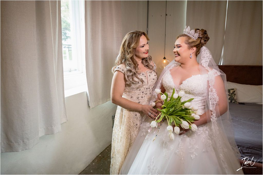 Two people sharing a joyful moment with white tulip bouquet in a sun-lit room.