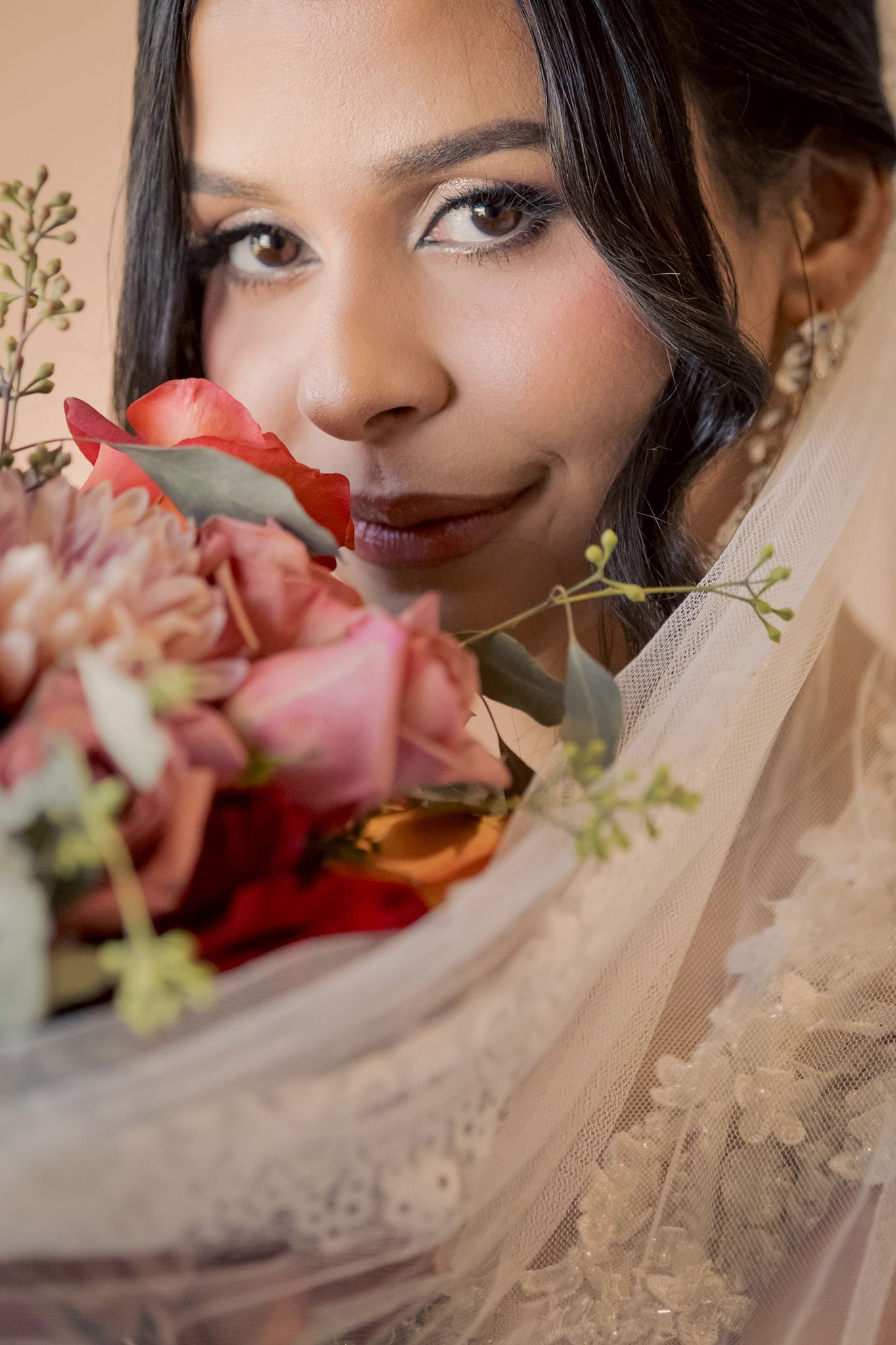 Close-up bridal portrait with pink roses and delicate veil details.