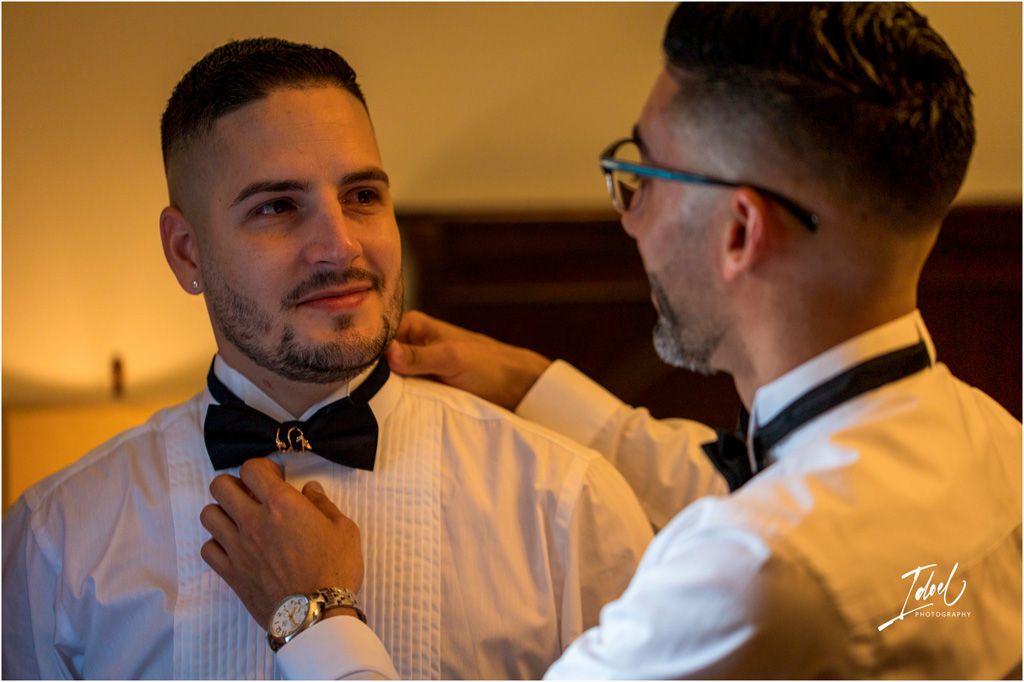 Two people in formal attire adjust bow ties while getting dressed for an elegant evening occasion.