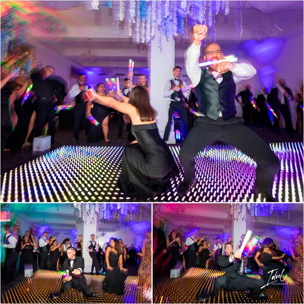 Wedding guests dancing energetically on an LED-lit dance floor under purple lighting and crystal chandeliers at a reception.