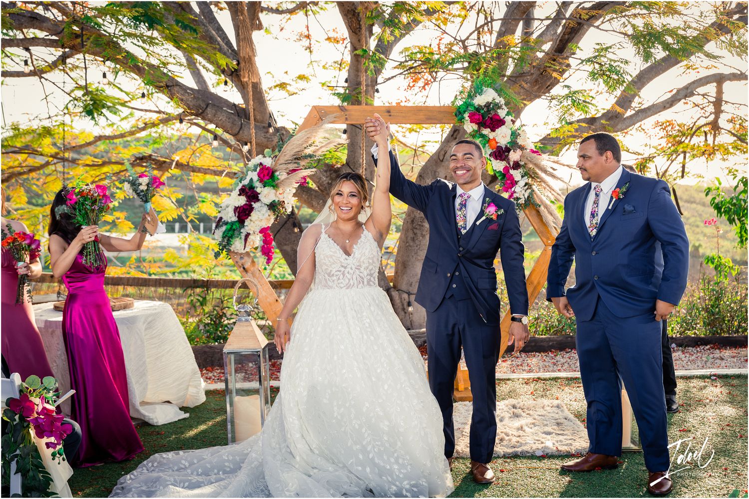 Celebratory moment at outdoor wedding ceremony with burgundy and navy color scheme.