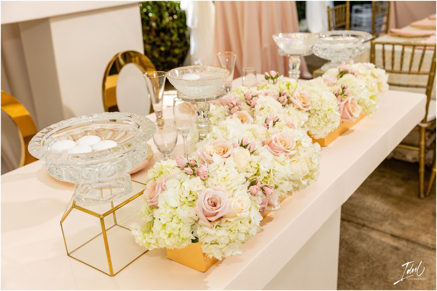 Elegant table decor with pink and white floral centerpieces and gold geometric accents.