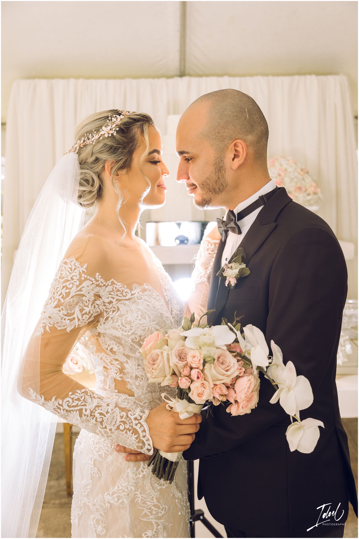 Intimate wedding portrait with soft lighting and delicate pink and white bouquet.