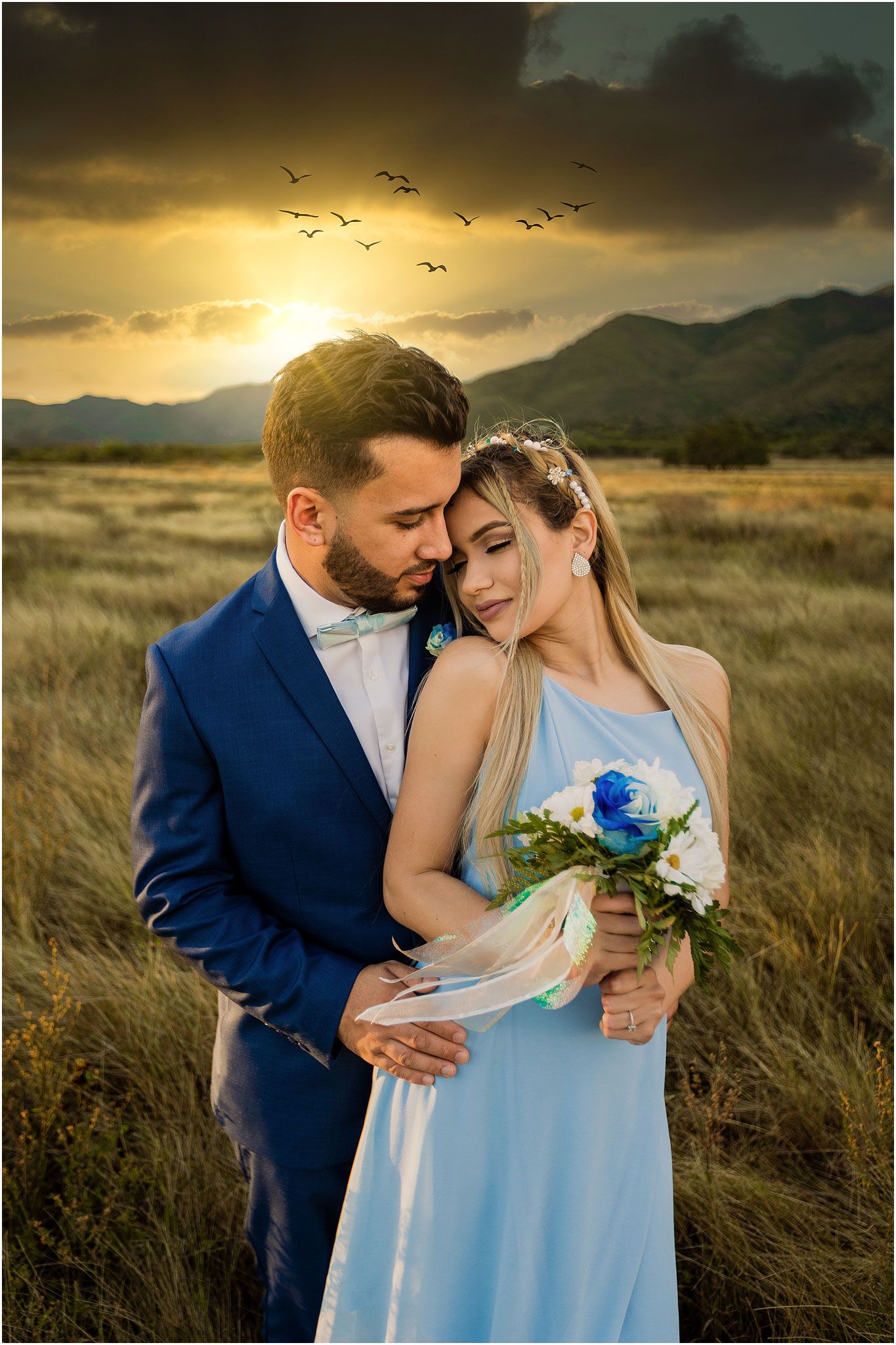 A tender embrace at sunset with birds flying overhead in a mountain landscape.