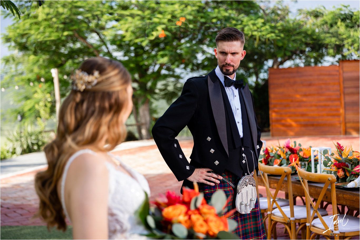 Garden wedding scene with decorative wooden arch and orange floral arrangements.