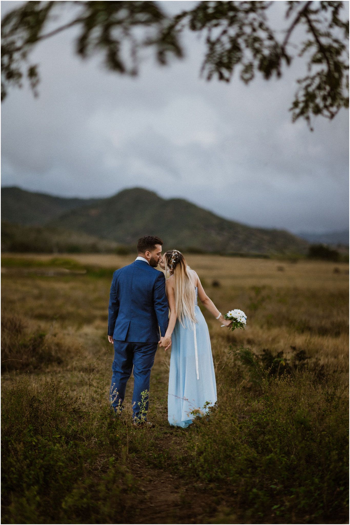 A couple shares an intimate moment on a mountain trail surrounded by nature.