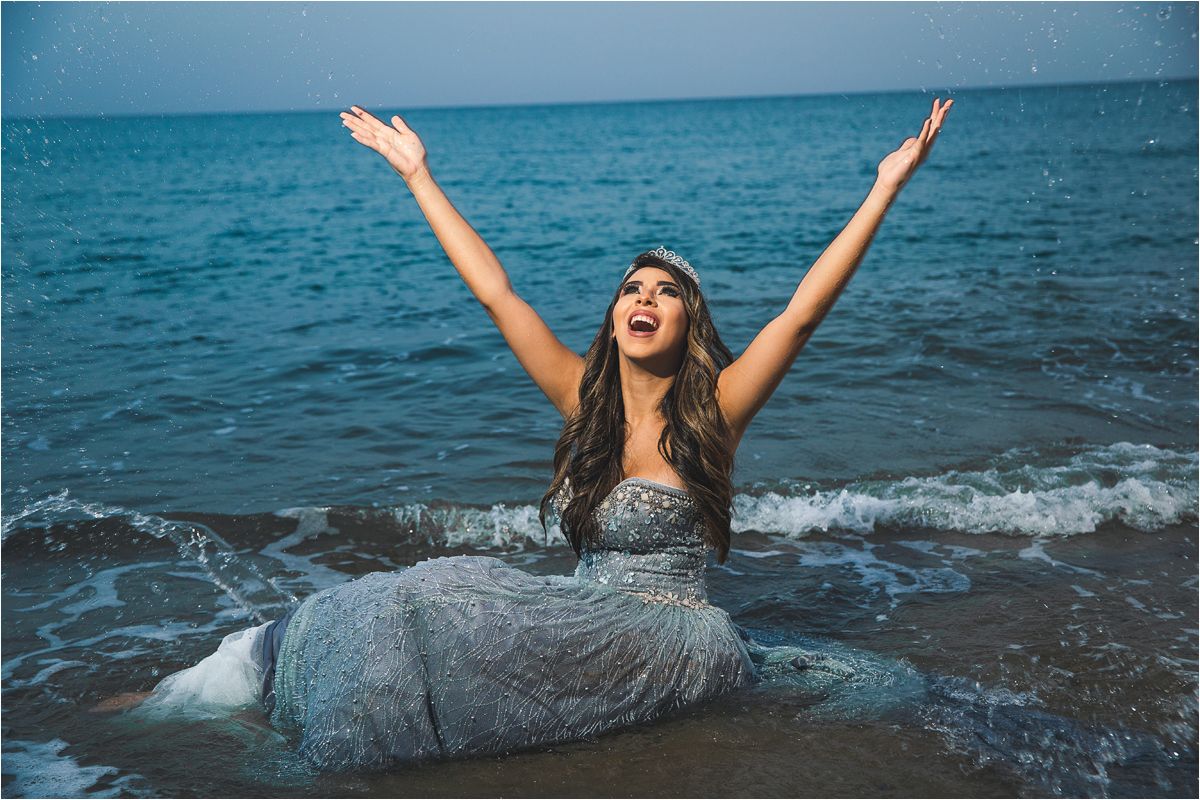 A joyful moment captured in a sparkly gray dress against the backdrop of turquoise ocean waves.