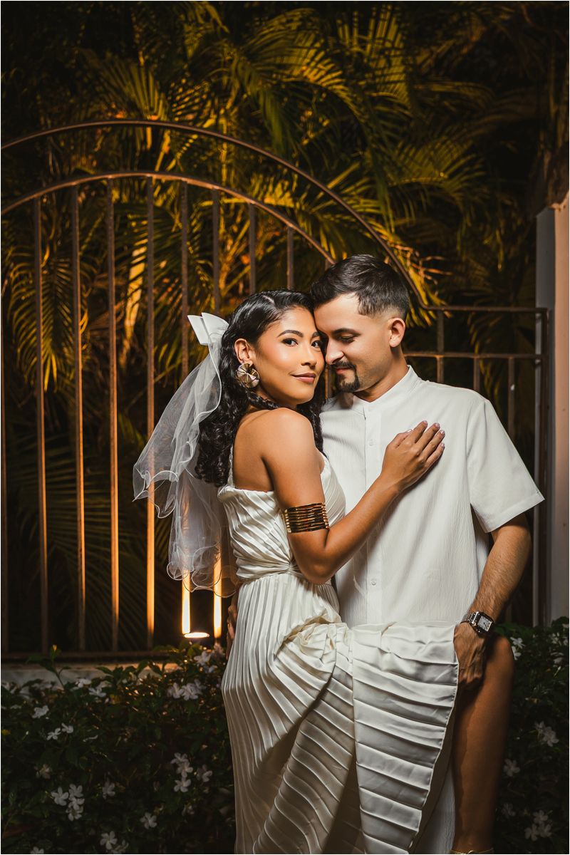 Intimate evening portrait with palm trees and dramatic lighting creating a romantic tropical ambiance.