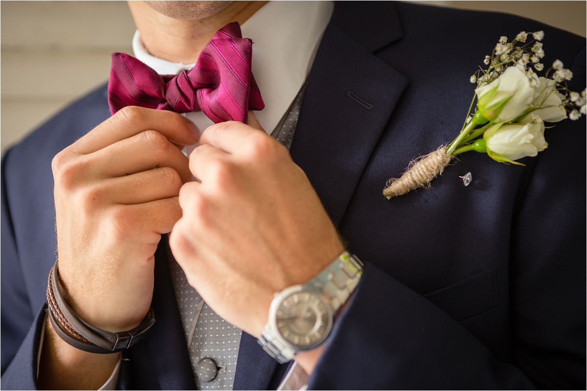 A groom pins a white boutonniere flower to his suit lapel in a wedding preparation sequence.