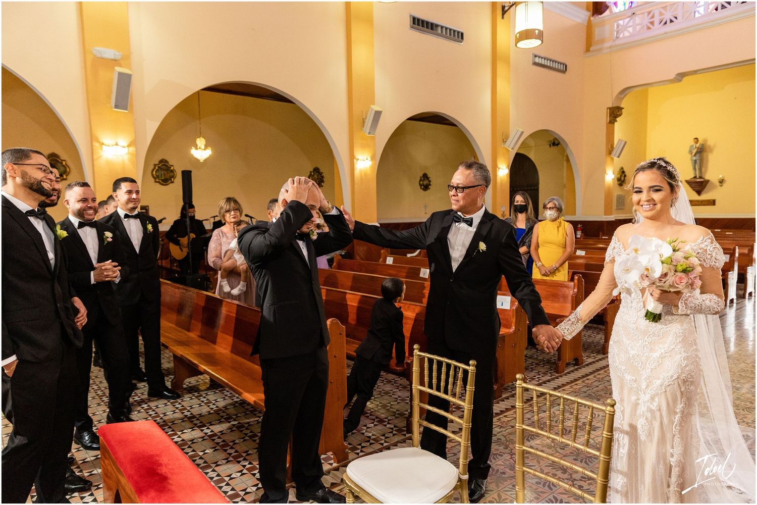 Wedding guests celebrate with raised hands during a joyful moment in a church ceremony.