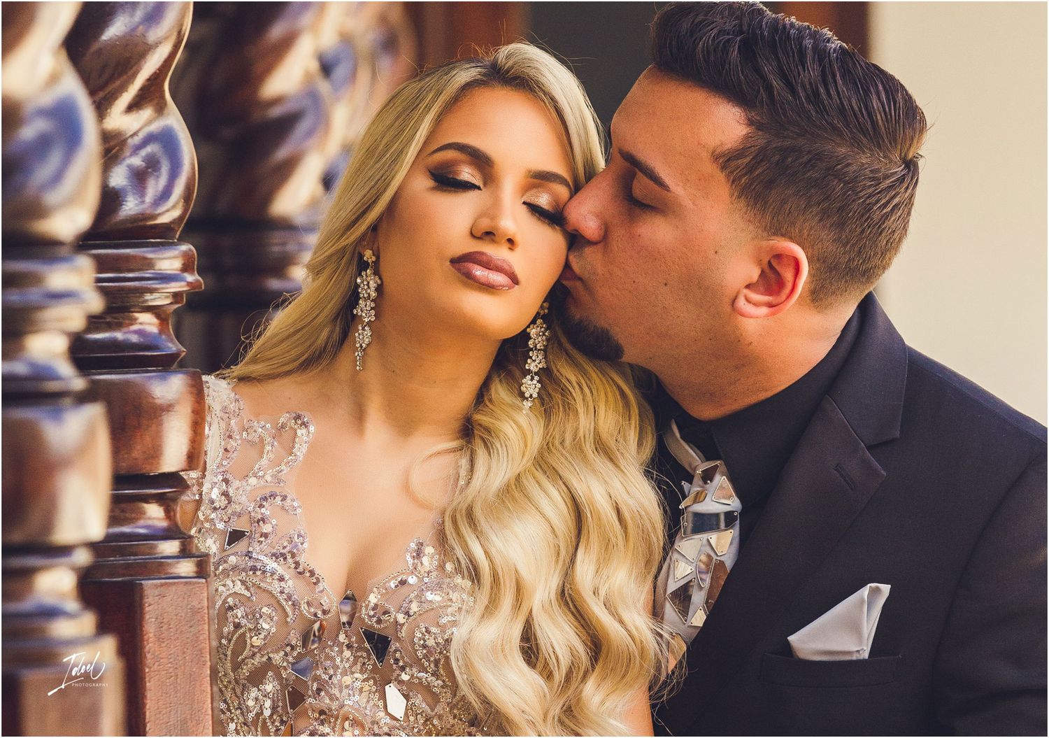 Intimate portrait of couple in formal attire with ornate details in background.