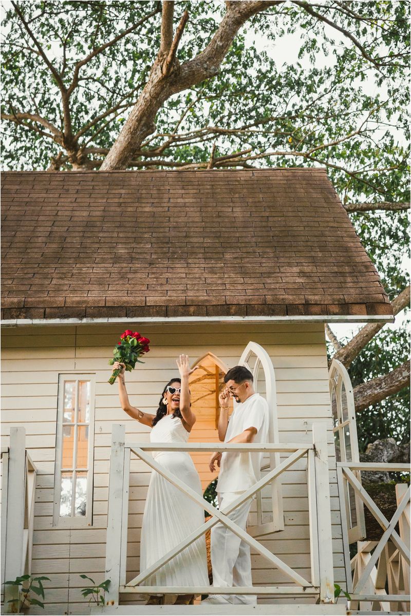A series of five connected white wooden cabins with figures in white dresses posing playfully on the porches.