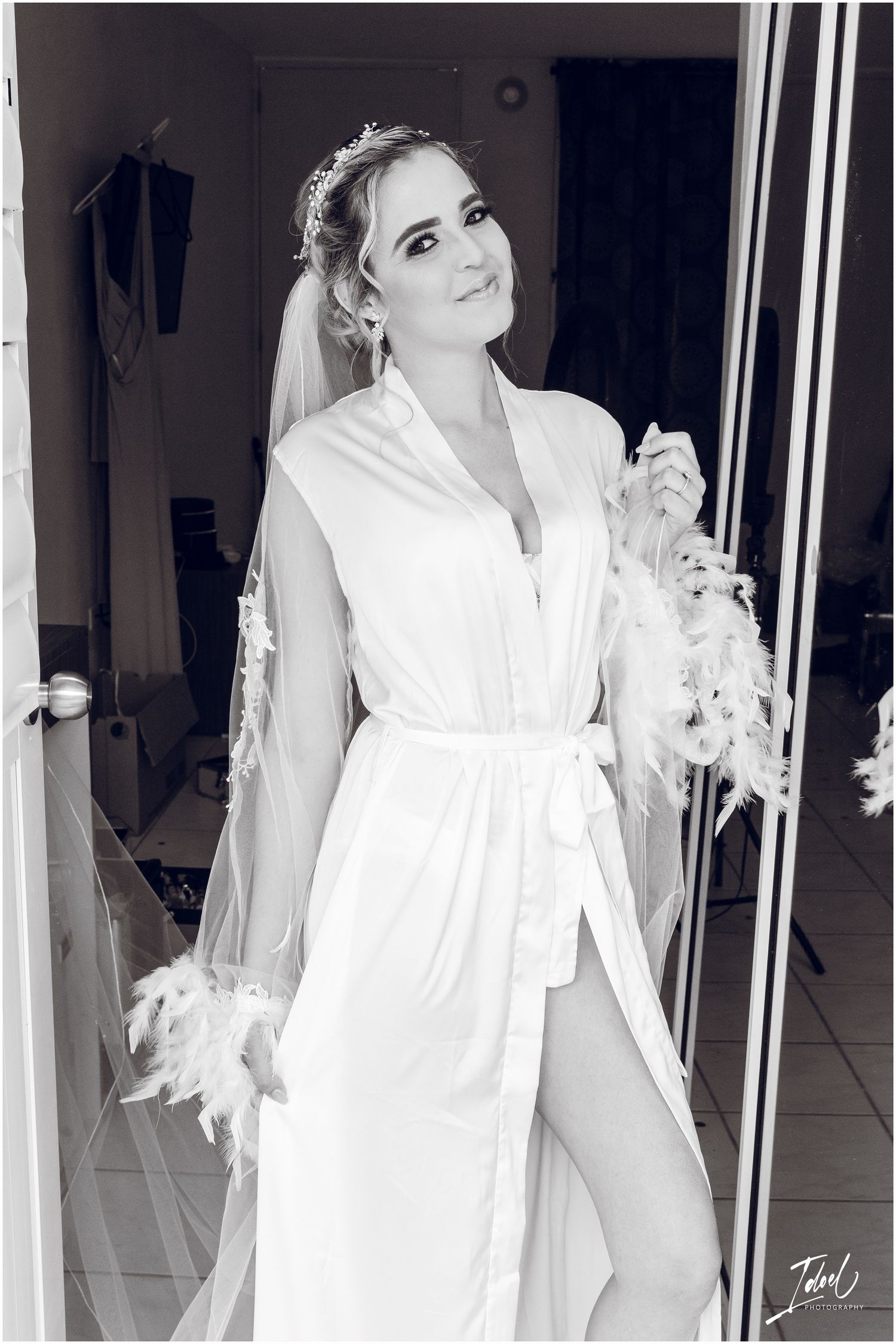 Black and white portrait of bride in silk robe with crystal headpiece and flowing veil.