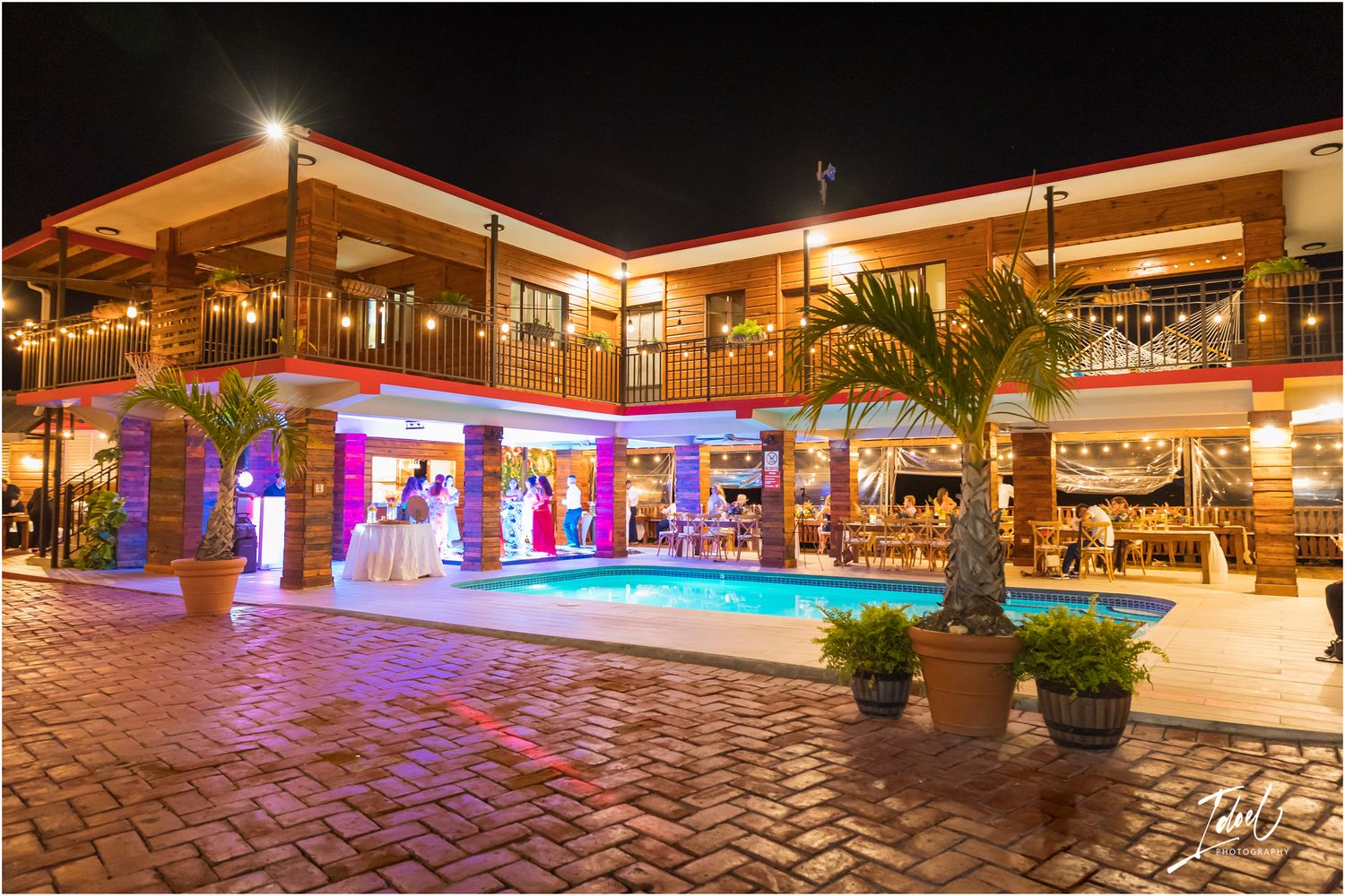 Modern shopping center lit up at night with palm trees and colorful LED lighting.