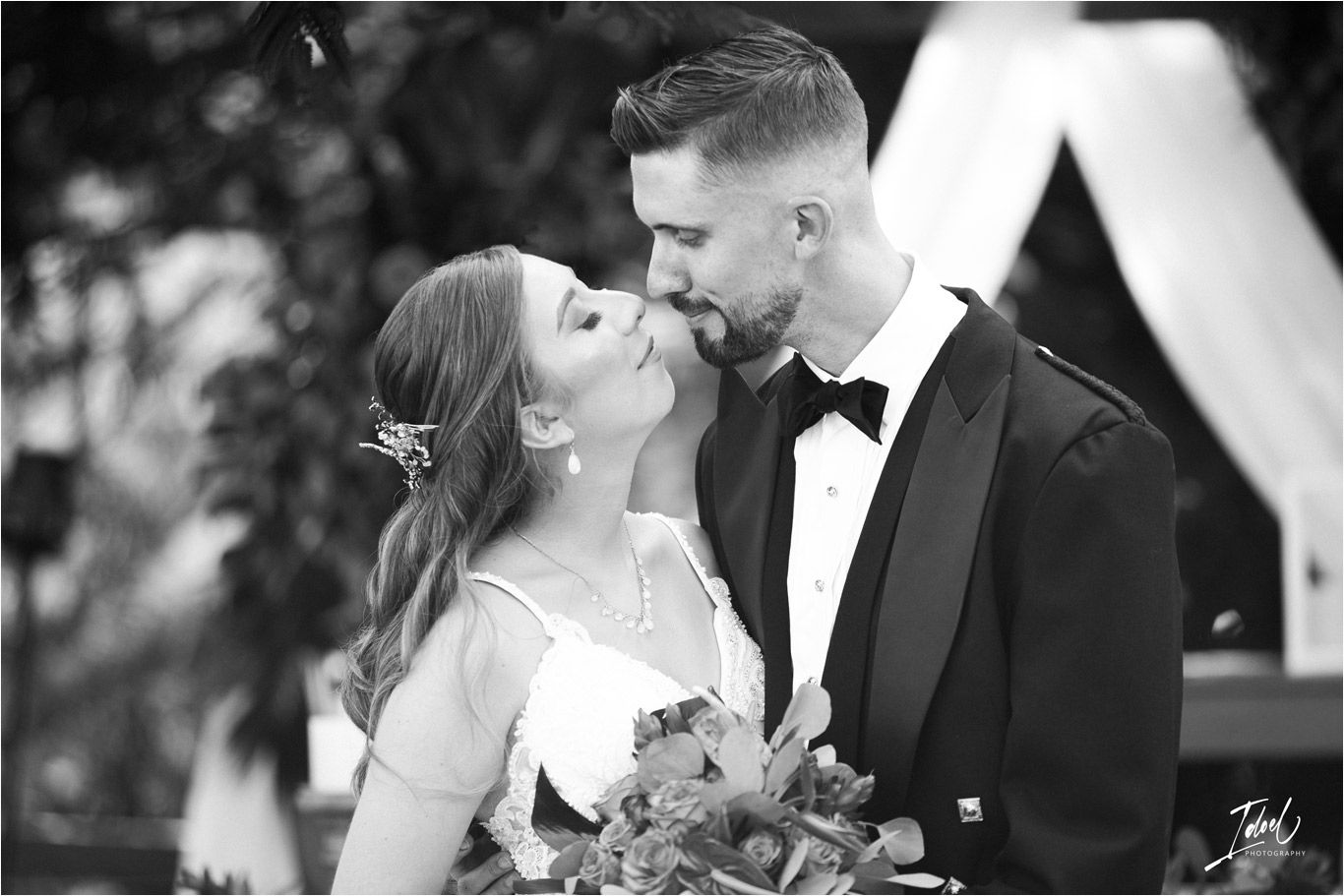 Black and white intimate wedding portrait showing tender moment between newlyweds.