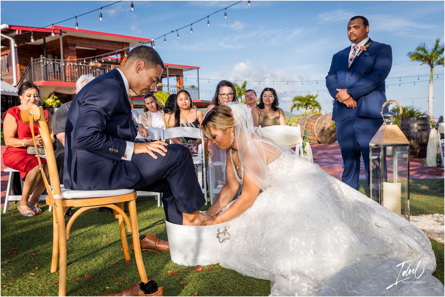 Newlyweds participate in a traditional wedding shoe game during an outdoor celebration.