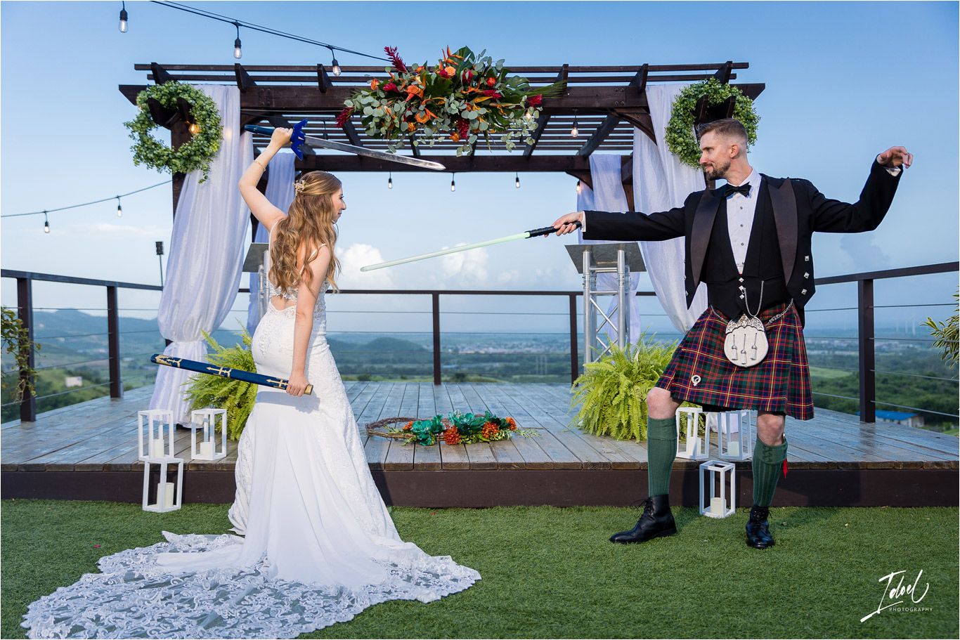 Couple strikes dramatic poses during wedding photoshoot under decorated outdoor pergola.