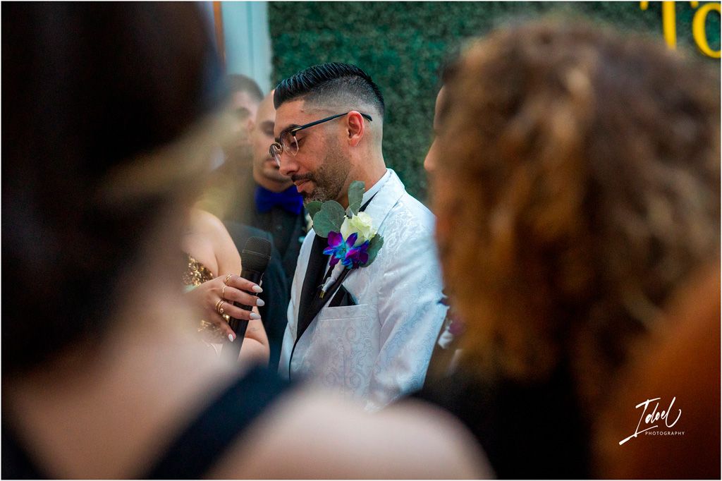 Two people sharing an intimate moment during an outdoor wedding ceremony while wearing formal attire and boutonnieres.