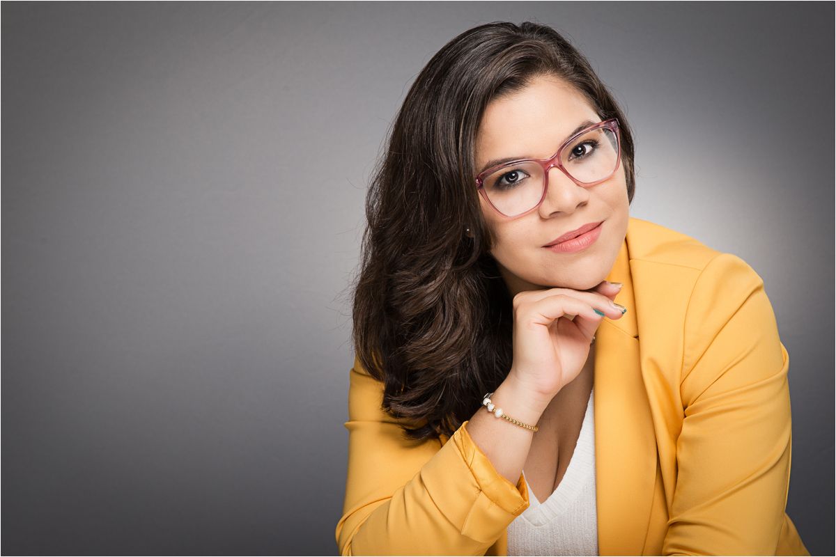 Professional headshot series showing person in bright yellow blazer posing against gray background in different angles.
