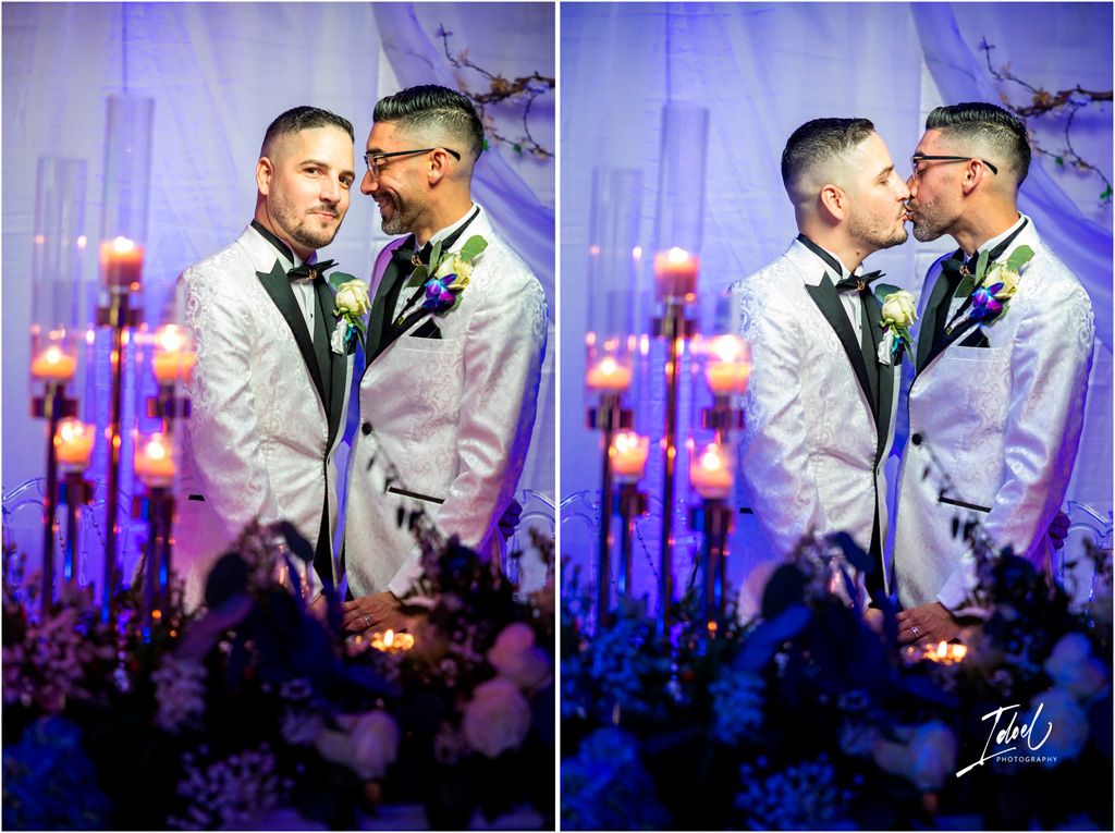 A romantic wedding moment captured in soft purple lighting with floral decorations in the foreground.