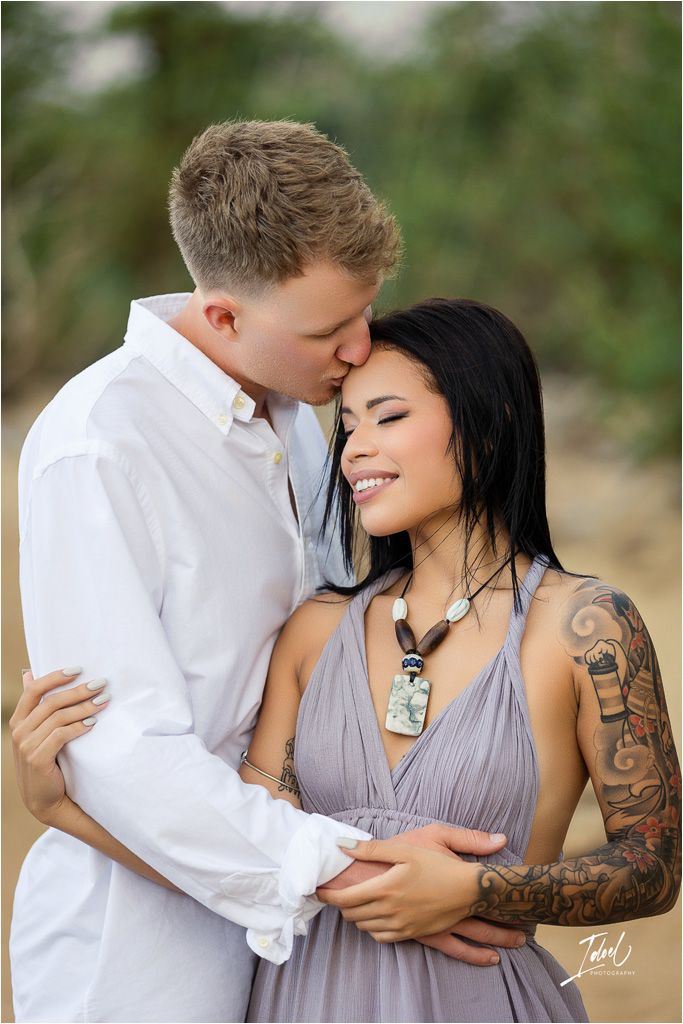 Romantic portrait on beach with artistic tattoo details.