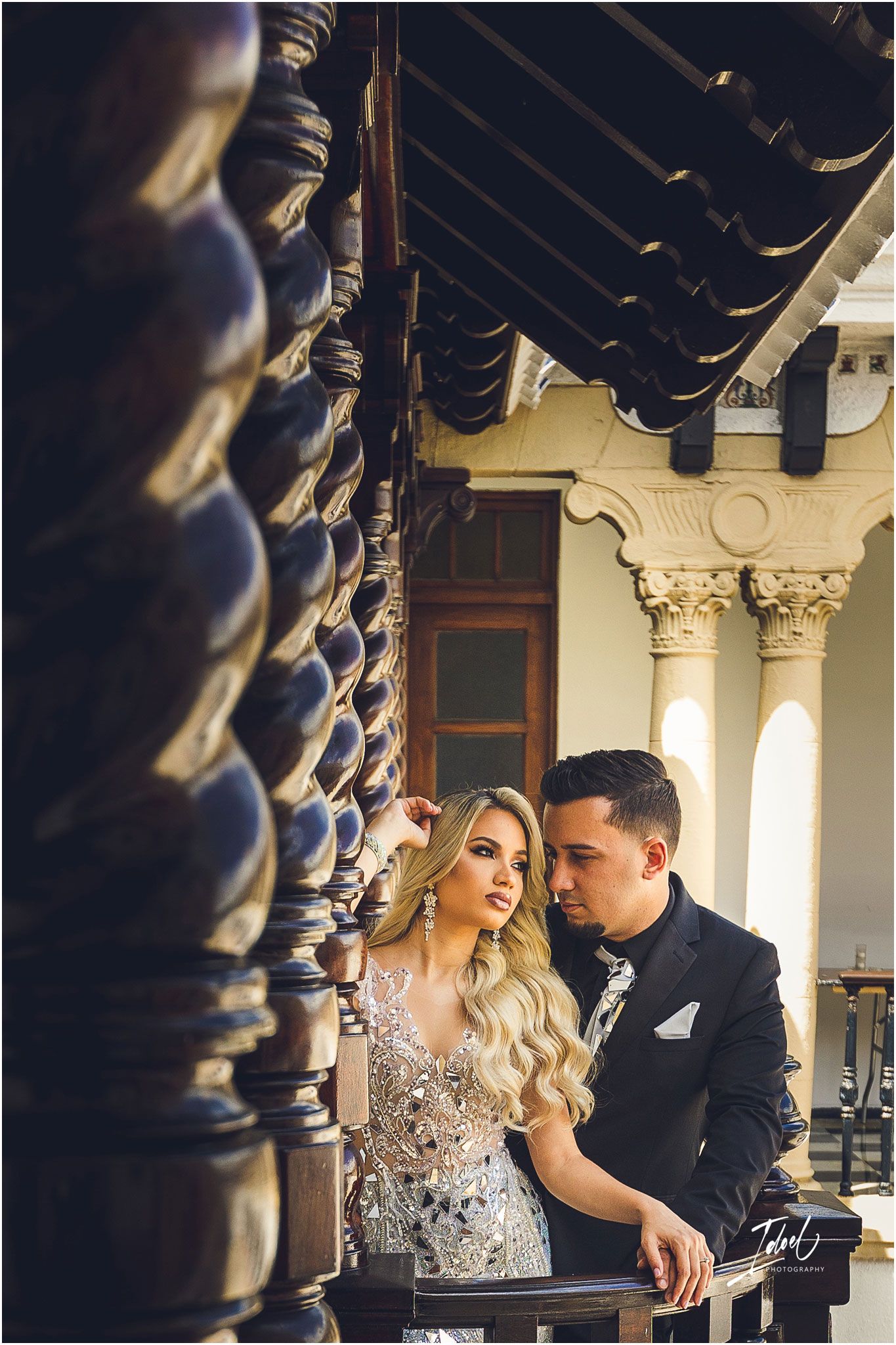 Artistic portrait on balcony with decorative wooden columns in historic building.